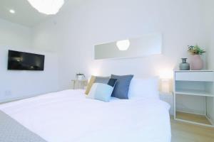 a white bedroom with a white bed with blue pillows at b hotel Ball Park - Apt 2mins to Baseball 5mins to Hiroshima Sta in Hiroshima