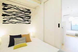 a bedroom with a white bed with a painting on the wall at b hotel Ball Park - Apt 2mins to Baseball 5mins to Hiroshima Sta in Hiroshima