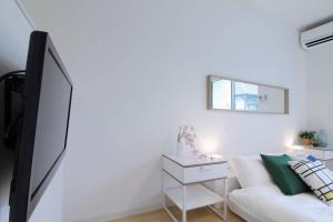 a living room with a white couch and a mirror at b hotel Ball Park - NewlyBuild 2 bedrm Apt 2 mins Baseball Museum 4ppl in Hiroshima +35 photos