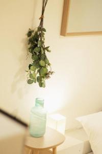 een vaas op een tafel met een plant die aan de muur hangt bij b hotel Ball Park - 2mins walk Baseball 5mins walk Hiroshima Sta 4ppl in Hiroshima