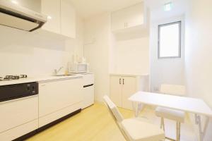 a kitchen with white cabinets and a table and chairs at bHOTEL Ball Park - 2mins walk Baseball 5mins walk Hiroshima Sta 4ppl in Hiroshima