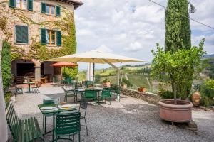 eine Terrasse mit Tischen, Stühlen und einem Sonnenschirm in der Unterkunft Savignola Paolina in Greve in Chianti