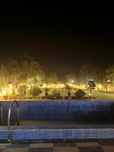 uma vista para uma piscina à noite em Marks Farm em Alwar