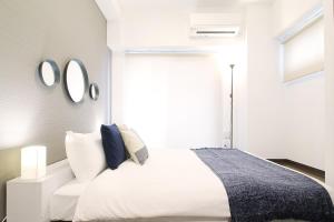 Un dormitorio con una cama blanca con espejos en la pared en bHotel 560 Comfy Elegant 1BR apartment for 4 people, en Hiroshima