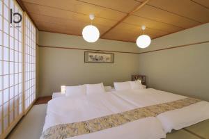 ein Schlafzimmer mit einem großen weißen Bett mit zwei Lampen in der Unterkunft Hanagin by b hotel - Large 2 bedroom apartment for 12people 301 in Hiroshima