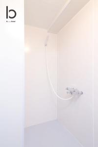 een douche in een badkamer met een witte muur bij Dai3Himawari - Stylish Apt 3mins walk PeacePark 4ppl in Hiroshima