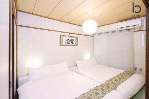 twee bedden in een kleine kamer met witte muren bij bHOTEL Dai3Himawari - Japanese Apt 3mins walk PeacePark 6ppl in Hiroshima