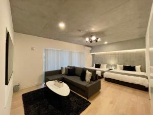 - un salon avec un canapé et 2 lits dans l'établissement bHOTEL Nekoyard - Scenic Penthouse Studio with Jacuzzi & Spacious Terrace, à Hiroshima