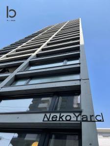 een hoog gebouw met een bord aan de zijkant bij bHOTEL Nekoyard - Brand new 1BR Apt for 7 ppl with loft Few Mins Walk To Peace Park in Hiroshima