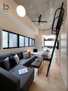 ein Wohnzimmer mit einem Sofa und einer Loft-Leiter in der Unterkunft bHOTEL Nekoyard - Brand new 1BR Apt for 7 ppl with loft Few Mins Walk To Peace Park in Hiroshima