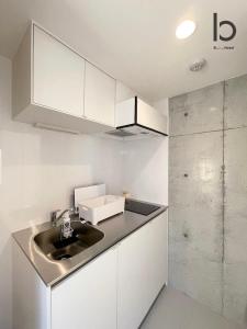 a kitchen with white cabinets and a sink at bHOTEL Nekoyard - Brand new 1BR Apt for 7 ppl with loft Few Mins Walk To Peace Park in Hiroshima