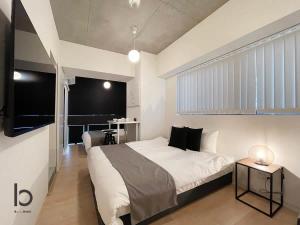a bedroom with a large white bed and a table at bHOTEL Nekoyard - 1BR Apartment, Good for 6 Ppl, Near Peace Park, WIFI Available in Hiroshima