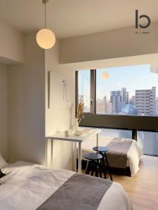 ein Schlafzimmer mit einem Bett und einem Tisch mit Aussicht in der Unterkunft b hotel Nekoyard - City-Center Studio, Secure & Close to Peace Park in Hiroshima + 40 Fotos