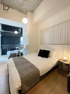 a bedroom with a large bed and a table at bHOTEL Nekoyard - 1 Bedroom with Loft Good For 7PPL Close To Peace Park in Hiroshima