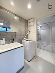 a white kitchen with a sink and a refrigerator at bHOTEL Nekoyard - 1 Bedroom with Loft Good For 7PPL Close To Peace Park in Hiroshima