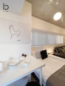 広島市にあるbHOTEL Nekoyard - NEW 1 BR Apartment, Near Peace Park, Good 6Pplのベッド1台、テーブル(皿付)が備わる客室です。
