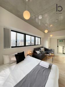 bHOTEL Nekoyard - NEW 1 BR Apartment, Near Peace Park, Good 6Ppl في هيروشيما: غرفة نوم بسرير ابيض كبير واريكة
