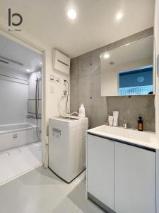 eine weiße Küche mit einer Spüle und einem Kühlschrank in der Unterkunft bHOTEL Nekoyard - NEW 1 BR Apartment, Near Peace Park, Good 6Ppl in Hiroshima