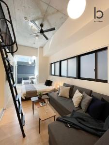 a living room with a couch and a bed at bHOTEL Nekoyard - Loft Studio Close to Peace Park & City Sights in Hiroshima