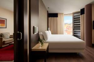 una camera d'albergo con un letto bianco e una finestra di NH Tenerife a Santa Cruz de Tenerife
