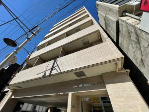 um edifício alto com um sinal em frente em bHOTEL Casaen - Brand New 1BR Apt Near Hondori Shopping District For 6 Ppl em Hiroshima