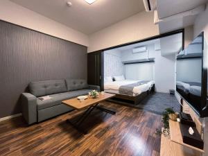 bHOTEL Casaen - Brand New 1BR Apt Near Hondori Shopping District For 6 Ppl في هيروشيما: غرفة معيشة مع أريكة وسرير وتلفزيون