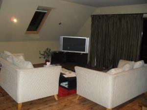 a living room with two white chairs and a television at Cityescape in Kaimai