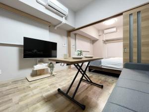 広島市にあるbHOTEL Casaen - 1BR Apartment with beautiful City View Near Shopping District For 6Pplのテーブル、テレビ、ベッドが備わる客室です。