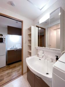 W białej łazience znajduje się umywalka i lodówka. w obiekcie bHOTEL Casaen - 1BR Apartment with beautiful City View Near Shopping District For 6Ppl w mieście Hiroszima