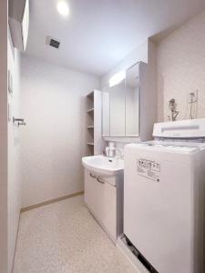 a small white bathroom with a sink and a refrigerator at bHOTEL Casaen - 1BR apartment in a quiet neighborhood, near Hondori Shopping Arcade in Hiroshima