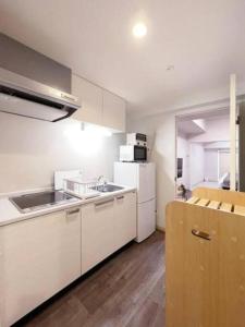eine Küche mit weißen Schränken und einem weißen Kühlschrank in der Unterkunft bHOTEL Casaen - Cozy 1BR Apt near Hondori District for 6 Ppl in Hiroshima