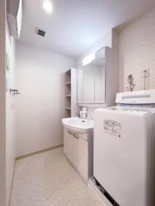 a small white kitchen with a sink and a refrigerator at bHOTEL Casaen - Cozy 1BR Apt near Hondori District for 6 Ppl in Hiroshima