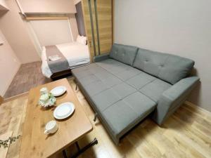 una sala de estar con un sofá y una mesa en Casaen by b hotel- Modern 1 BR near Hondori District for 6 Ppl, en Hiroshima