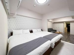 Un dormitorio con una cama grande y una sala de estar en Casaen by b hotel- Modern 1 BR near Hondori District for 6 Ppl, en Hiroshima