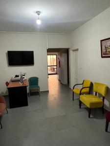 達喀爾的住宿－COMPLEXE BLUE PHOENIX，客厅配有椅子、桌子和电视