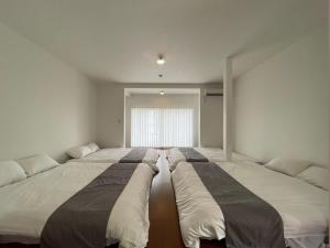 呉市にあるbLOCAL Sugawa House - 1 Bedroom House with Beautiful Ocean View for 12 Pplの大きな窓付きの客室で、ベッド3台が備わります。