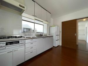 cocina con armarios blancos y nevera blanca en bLOCAL Sugawa House - 1 Bedroom House with Beautiful Ocean View for 12 Ppl en Kure