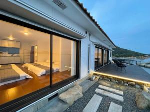 呉市にあるbLOCAL Sugawa House - 1 Bedroom House with Beautiful Ocean View for 12 Pplのバルコニー(ベッド2台付)、ベッドルーム1室が備わる家です。
