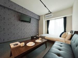 a room with a bed and a couch and a table at bHOTEL Nagomi - Beautiful 1 BR New Apt City Center for 3 Ppl in Hiroshima