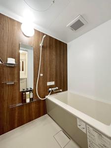 a bathroom with a bath tub and a mirror at bHOTEL Nagomi - Beautiful 1 BR New Apt City Center for 3 Ppl in Hiroshima +21 photos