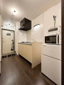 y cocina con fogones y microondas. en bHOTEL Nagomi - Well-Furnished with balcony Apt for 3 Ppl, en Hiroshima