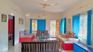 a living room with blue curtains and a couch at Spring Farm Ville in Alibaug