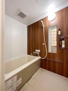 uma casa de banho com uma banheira e um espelho. em bHOTEL Nagomi - Well-Furnished with balcony Apt for 3 Ppl em Hiroshima