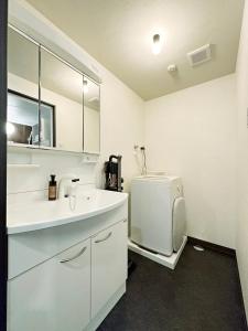 uma casa de banho branca com um lavatório e um frigorífico em bHOTEL Nagomi - Beautiful 2BR Apt City Center for 10 Ppl em Hiroshima