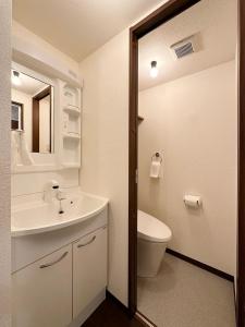 a bathroom with a sink and a toilet and a mirror at bHOTEL Nagomi - Well-Furnished with balcony Apt for 3 Ppl in Hiroshima
