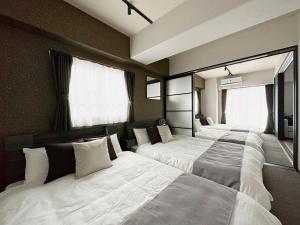 a bedroom with three beds and two windows at bHOTEL Nagomi - Large 2BR Apt City Center for 10 Ppl in Ōsukachō