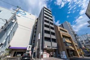 a tall building on a city street with buildings at bHOTEL Nagomi - Large 2BR Apt City Center for 10 Ppl in Ōsukachō