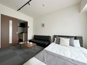 bHOTEL Nagomi - Comfy Apartment for 3 people near City Center في هيروشيما: غرفة نوم بسرير واريكة
