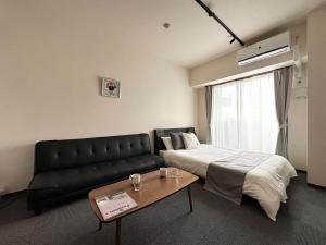 广岛Nagomi by b hotel - Comfy Apartment for 3 people near City Center的一间有床、沙发和桌子的房间