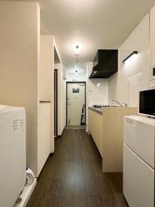 kuchnia z białymi urządzeniami i długi korytarz w obiekcie bHOTEL Nagomi - Comfy Apartment for 3 people near City Center w mieście Hiroszima